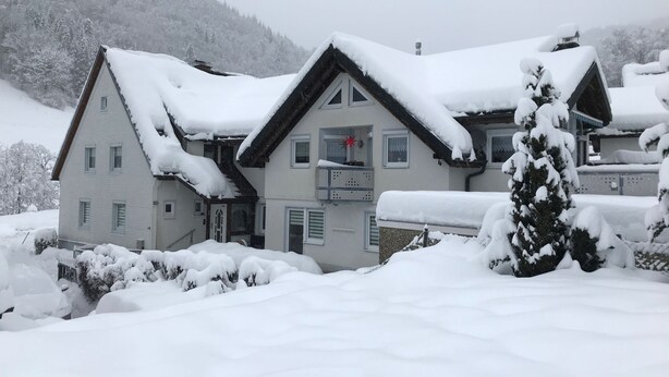 A two-story house with a snow-covered roof and a visible chimney. - Apartment 'Ella' with Mountain View, Private Terrace and Wi-Fi (Todtnau)