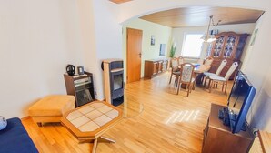A room with a wooden floor, a small table with a chair, a cabinet, and a television. - Apartment 'Ella' with Mountain View, Private Terrace and Wi-Fi (Todtnau)