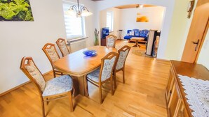 A dining area with a wooden table and chairs, a blue bowl, and a hanging light fixture. - Apartment 'Ella' with Mountain View, Private Terrace and Wi-Fi (Todtnau)