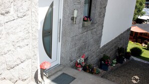 A stone building with a white door, a small window with flowers, and a garden with a gnome statue.