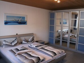 Een slaapkamer met een bed, een nachtkastje, een schilderij en een garderobe.