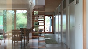 A modern interior with a glass partition, wooden flooring, and a dining area with chairs and a table. - Holiday Home 'Am Teich' with Mountain View, Private Terrace and Wi-Fi (Sankt Leonhard bei Freistadt)