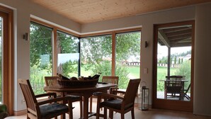 A dining area with a round table, wooden chairs, and a basket of bottles. - Holiday Home 'Am Teich' with Mountain View, Private Terrace and Wi-Fi (Sankt Leonhard bei Freistadt)