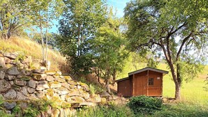 A wooden cabin with a stone wall and a small pond in front. - Holiday Home 'Am Teich' with Mountain View, Private Terrace and Wi-Fi (Sankt Leonhard bei Freistadt)