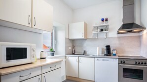 Una cocina moderna con armarios blancos, microondas, cafetera y estufa.