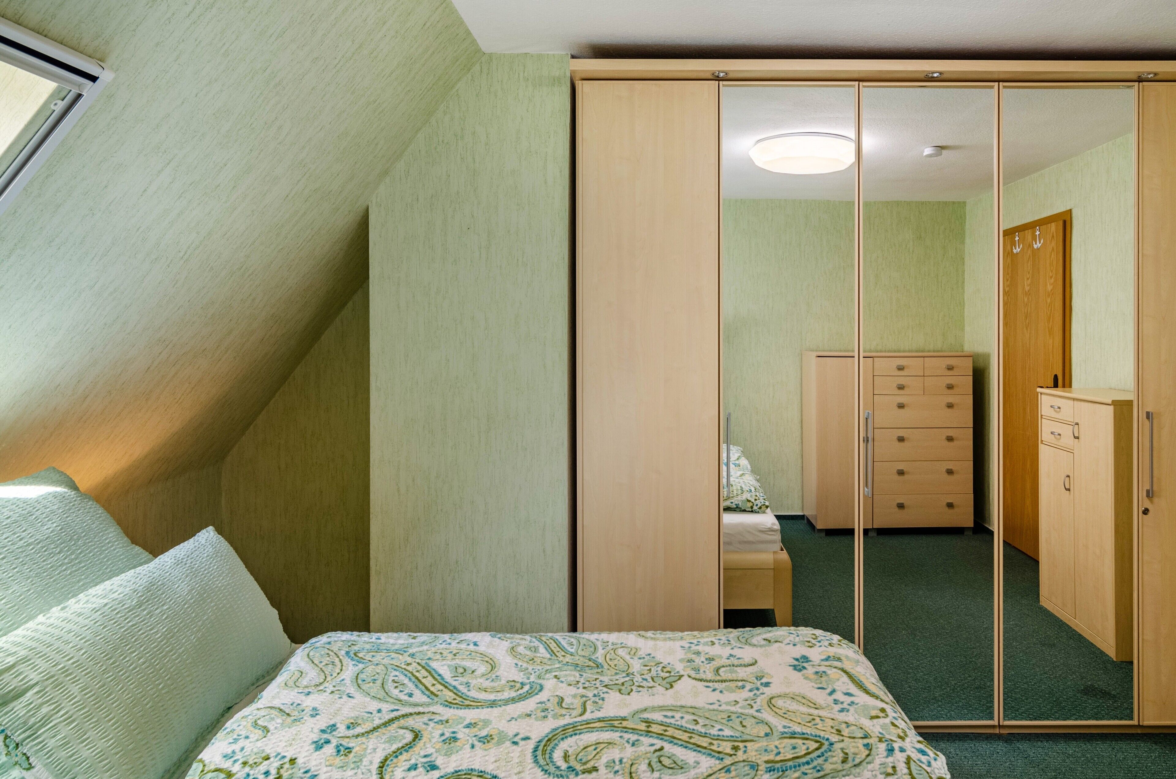 Ein Schlafzimmer mit Bett, Kleiderschrank, Schminktisch und Spiegel.
