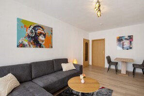 Una sala de estar moderna con un sofá gris, una mesa redonda de centro y dos cuadros en las paredes.