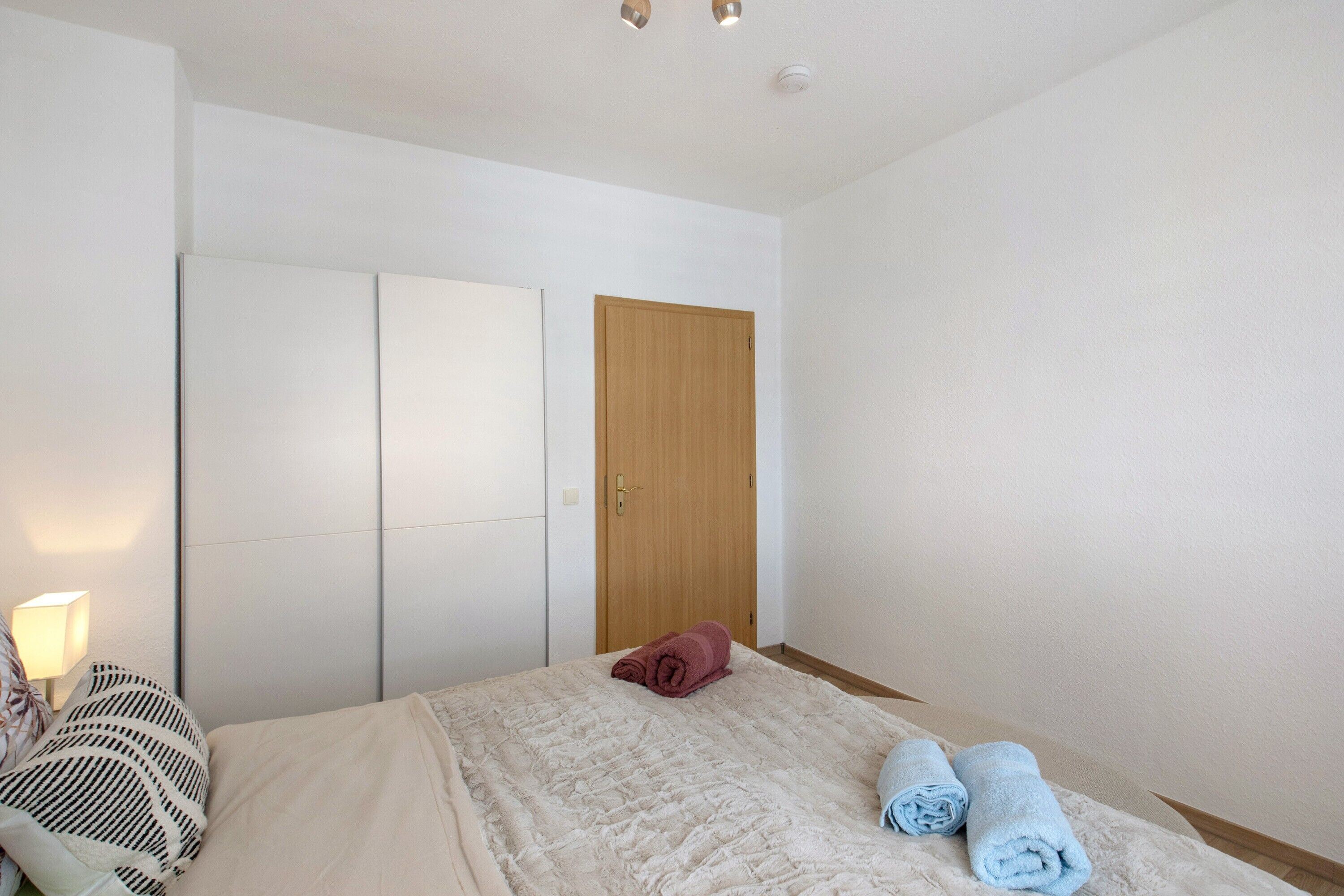 Ein Schlafzimmer mit einem Bett, einer Holztür und einem Nachttisch mit einer Lampe.