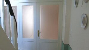 Un corridoio con una porta bianca, una scala e un muro decorato con piatti.