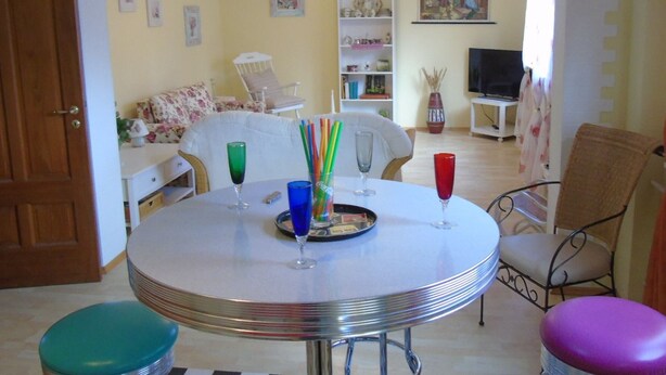 Zona pranzo con un tavolo rotondo, sedie e una televisione sullo sfondo.