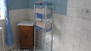 Un bagno con un armadietto in legno, un portasci con asciugamani piegati e un quadro appeso al muro.
