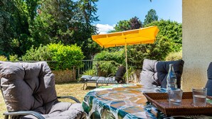 An outdoor patio with a table, chairs, and a yellow umbrella.