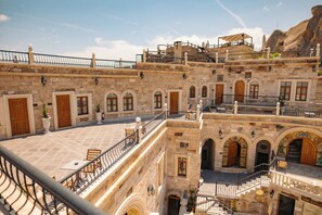 A multi-story building with stone architecture, balconies, and outdoor seating areas. -  The Kingdom Of Cappadocia Luxury Cave Hotel (Nevsehir)