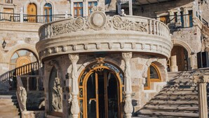 Un edificio histórico con elaborada decoración de piedra, una entrada central con arco y una escalera que conduce a un nivel superior.