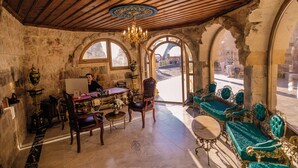 Una habitación con techo de madera, ventanas arqueadas, candelabro y muebles antiguos.