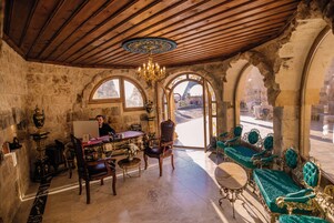 Una habitación con techo de madera, ventanas arqueadas, candelabro y muebles antiguos.