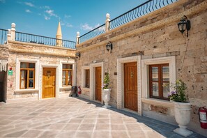A courtyard with stone flooring, wooden doors, and a tiled roof.