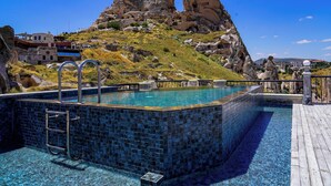 Une piscine avec un bord carrelé, une échelle en métal et une terrasse en bois.