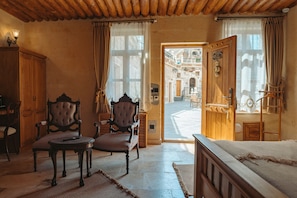 A room with a bed, two chairs, a table, and a wooden cabinet.