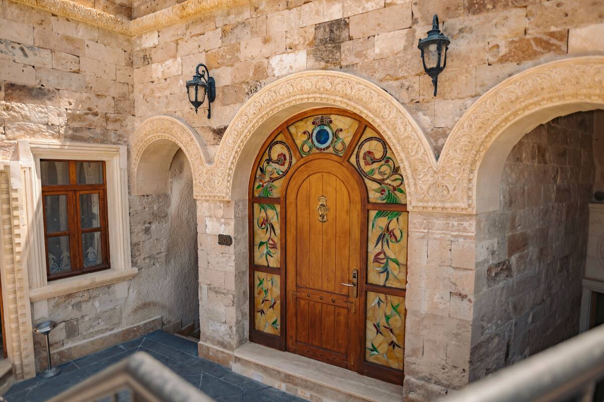 Un edificio de piedra con puerta de madera, arcos y una ventana.
