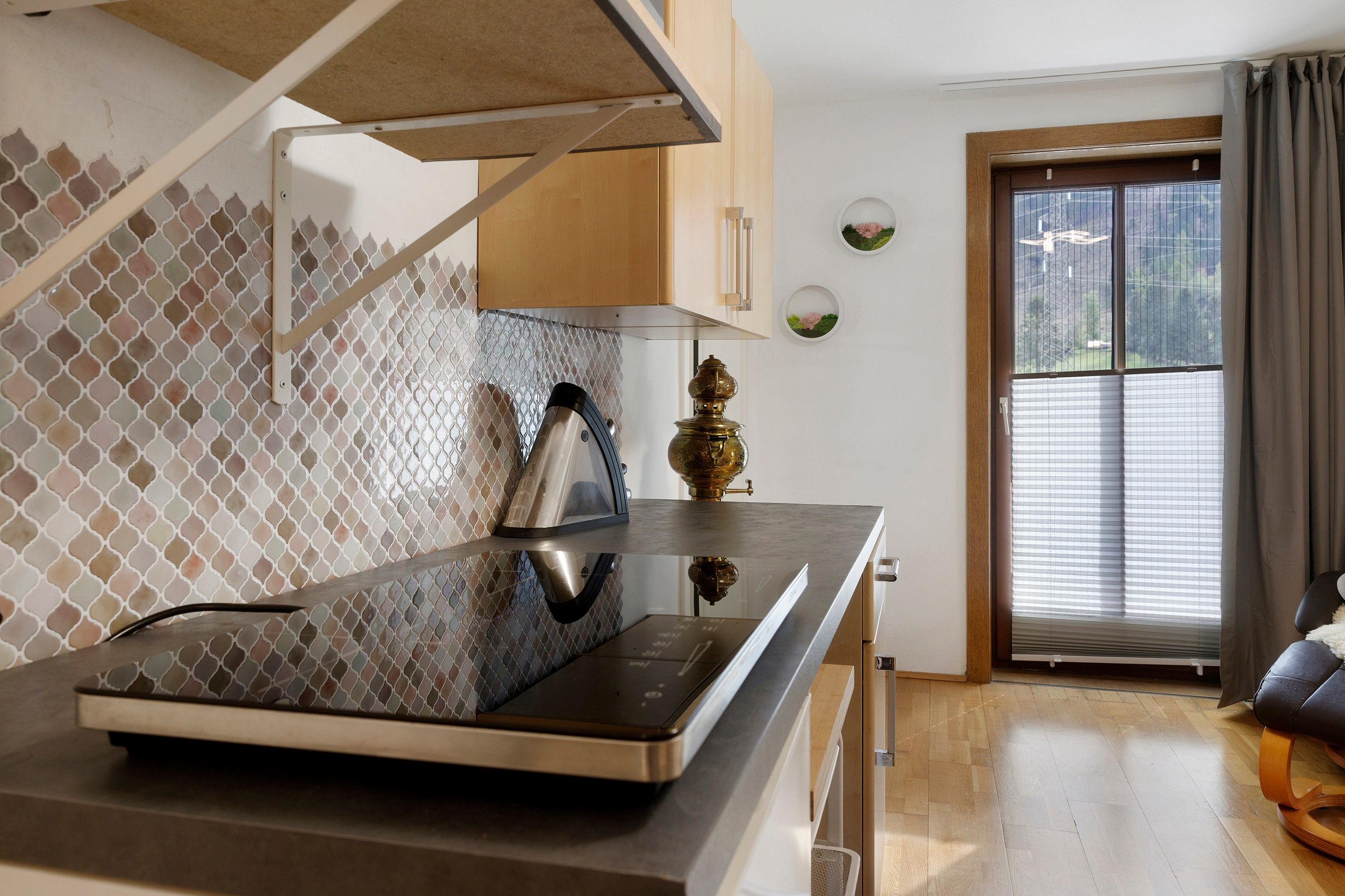 Una cocina moderna con estufa integrada, cafetera y ventana con persianas.