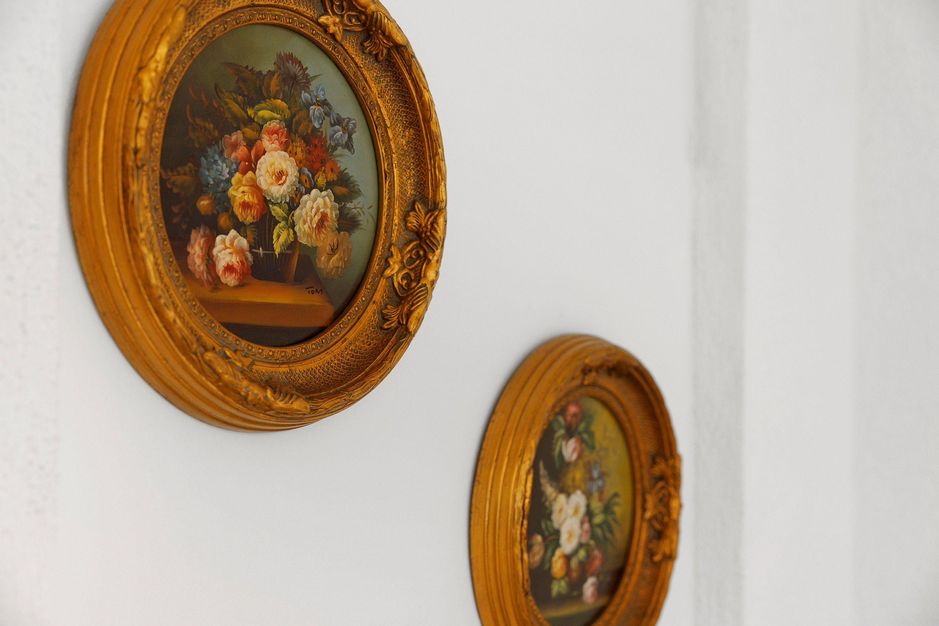Zwei gerahmte Blumenbilder an einer weißen Wand.