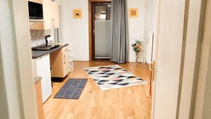 En hall som leder till ett kök med en matplats, en dörr med en gardin och en liten växt.