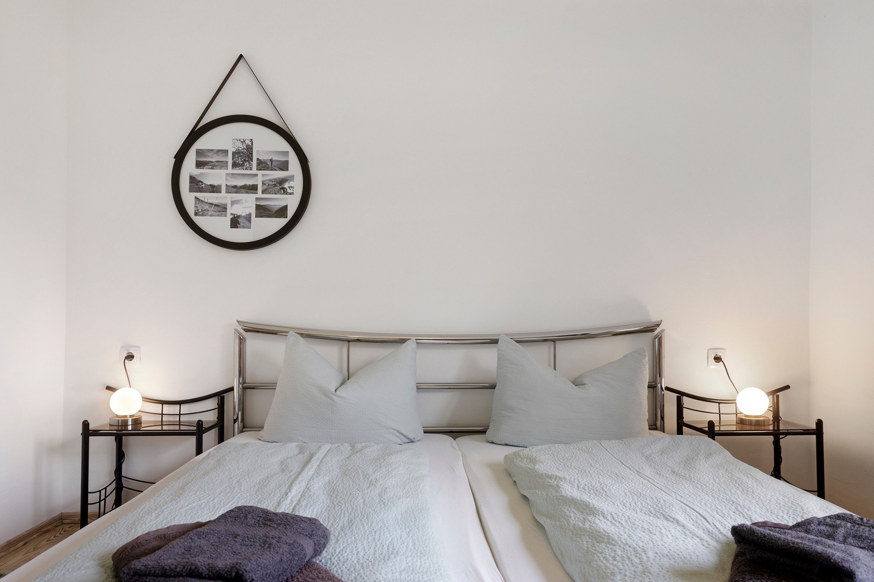 A double bed with a headboard, two bedside tables with lamps, and a framed photo collage on the wall.