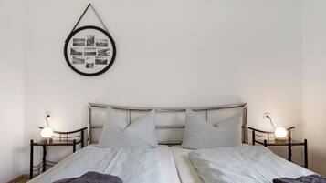 A double bed with a headboard, two bedside tables with lamps, and a framed photo collage on the wall.