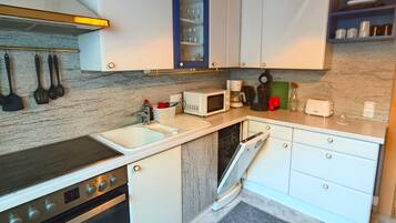 A modern kitchen with white cabinets, a built-in microwave, a stove, and a dishwasher.
