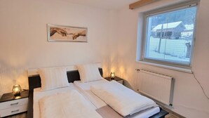 A bedroom with a bed, bedside tables, a window with blinds, a radiator, and a painting on the wall. - Apartment 'Gina' with Mountain Views, Private Garden and Wi-Fi (Stall)