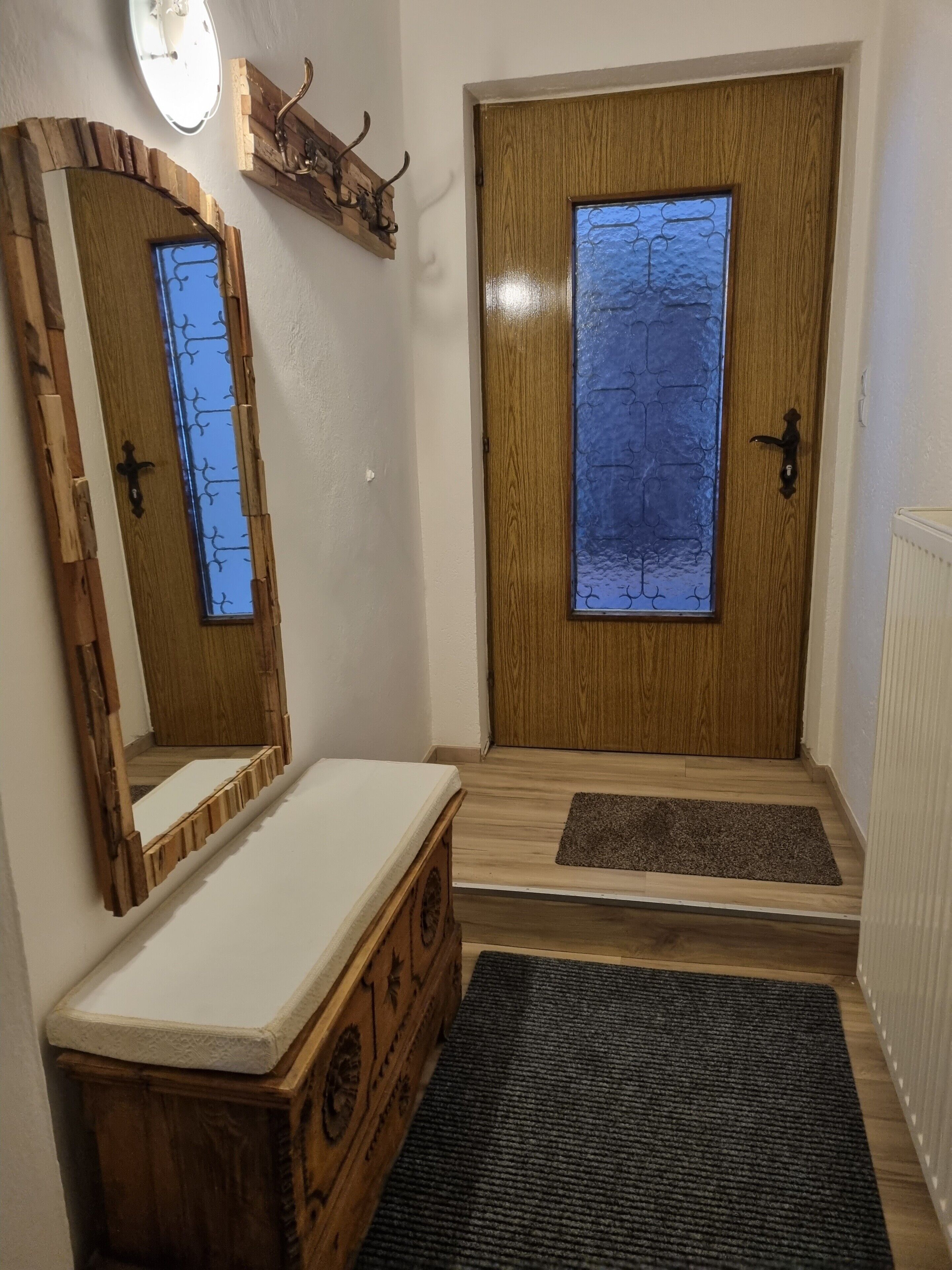 A wooden door with a window, a wooden dresser, and a mirror.