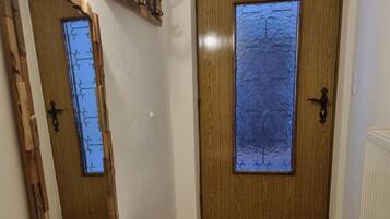A wooden door with a window, a wooden dresser, and a mirror.