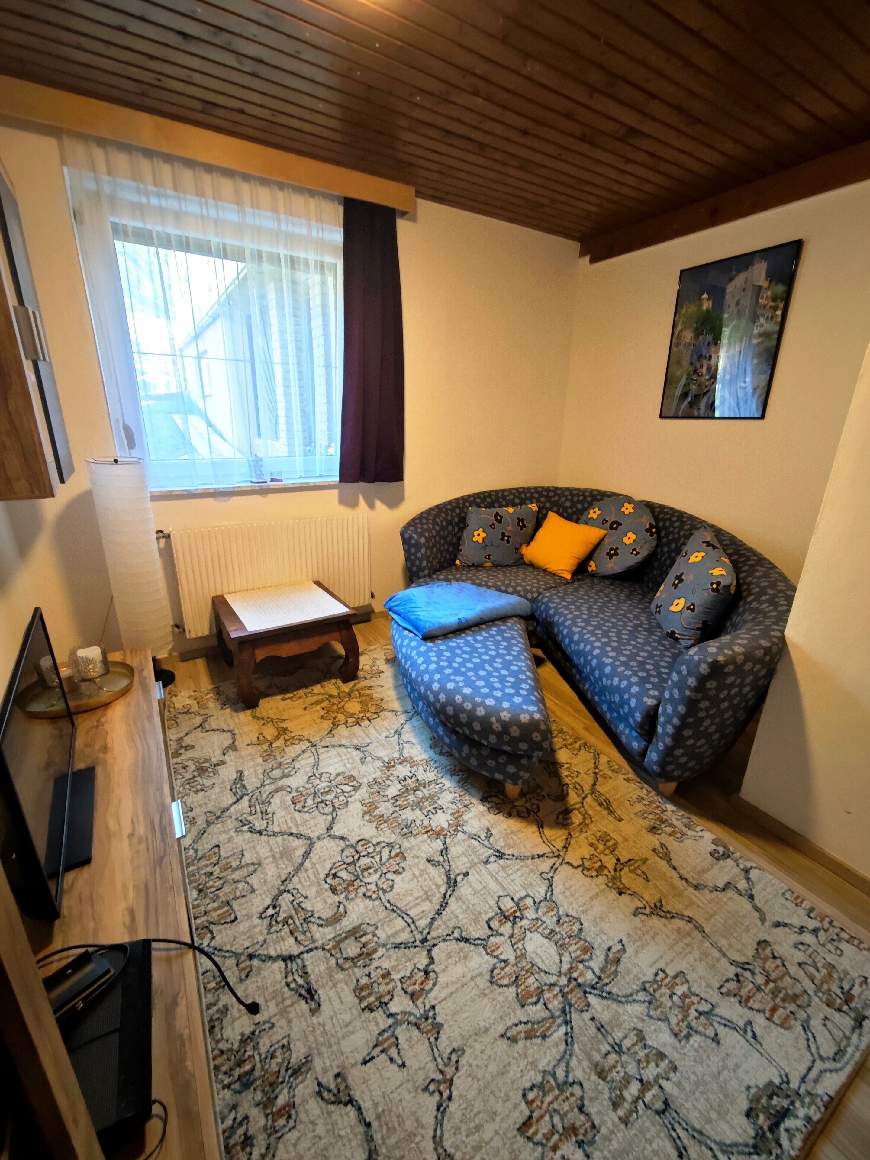 En hyggelig stue med sofa, skammel og et lille bord.
