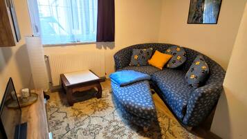 En hyggelig stue med sofa, skammel og et lille bord.