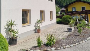 A building with a sign reading 'Gasthof zur Brücke' with multiple windows and a paved area with potted plants. - Apartment 'Gina' with Mountain Views, Private Garden and Wi-Fi (Stall)