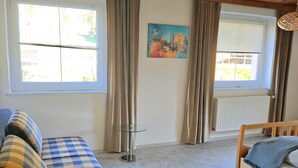 A room with a wooden ceiling, a sofa with checkered cushions, a small glass table, and a bed with a blue blanket. - Apartment 'Gina' with Mountain Views, Private Garden and Wi-Fi (Stall)
