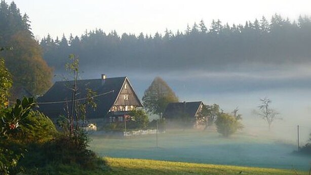 A rural landscape with two houses, a road, and a foggy field. - 'Gartenblick' Apartment with Mountain View, Private Terrace, and Wi-Fi (Schramberg)