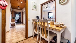 Een eetgedeelte met een houten tafel, stoelen, een klok en een spiegel aan de muur.