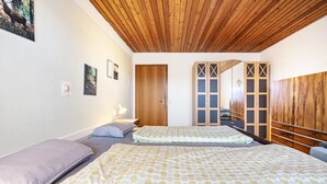 Een slaapkamer met twee bedden, een houten plafond en een kledingkast met spiegeldeuren.