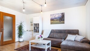 Een woonkamer met een bruine bank, een witte salontafel en een potplant.