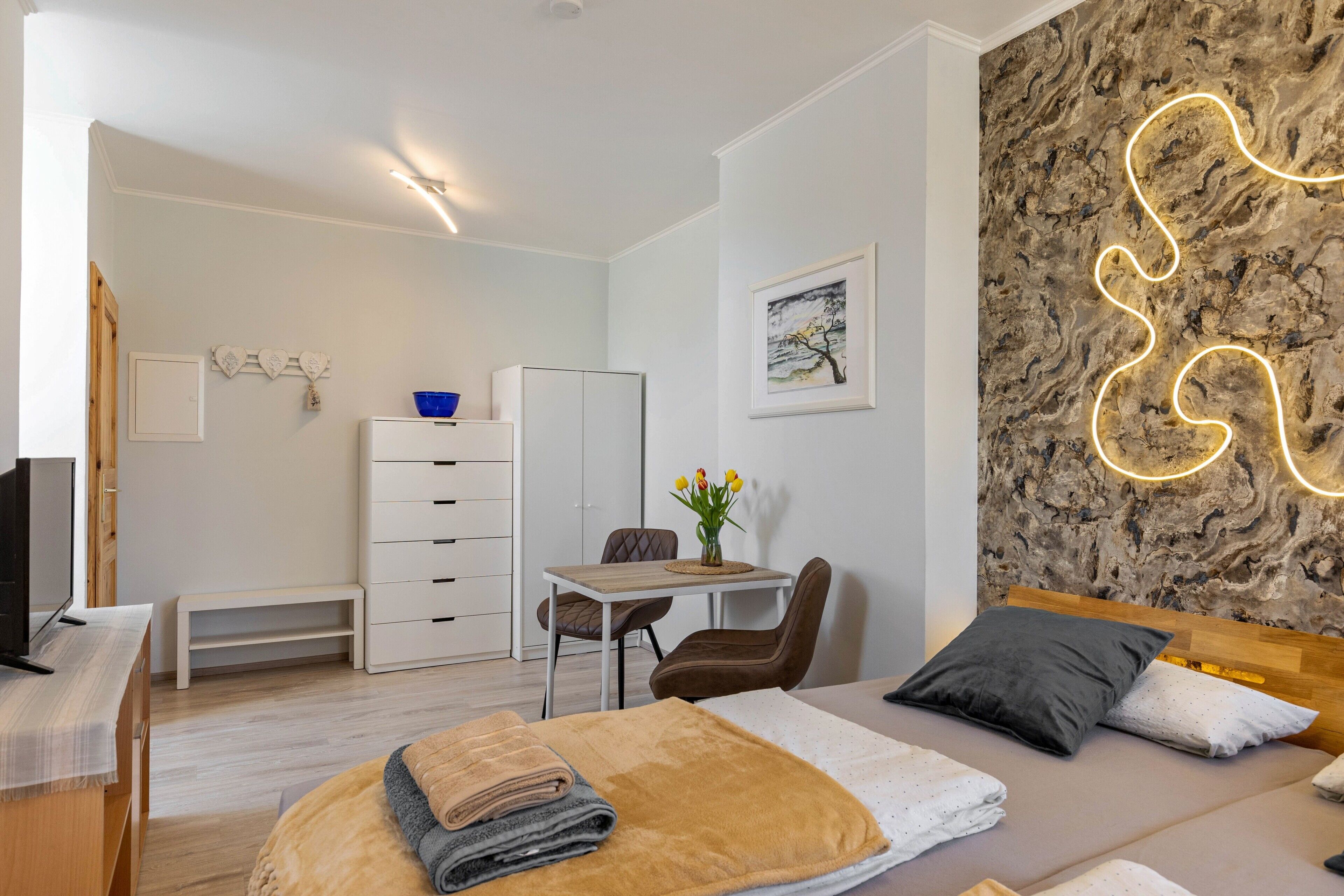 A modern bedroom with a bed, bedside table, and a desk with a chair.
