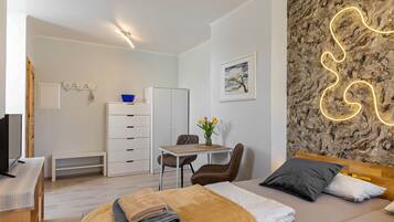 A modern bedroom with a bed, bedside table, and a desk with a chair.