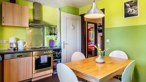 A kitchen with wooden cabinets, a stove, and a dining table with chairs. - Apartment 'Blackforest' with Shared Terrace, Shared Garden and Wi-Fi (Sankt Georgen)