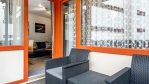A room with a sofa, a chair, and a window with patterned curtains.