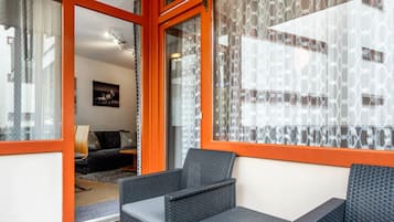 Une pièce comprenant un canapé, un fauteuil et une fenêtre ornée de rideaux à motifs.
