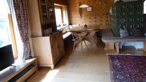 A wooden interior with a dining table, cabinets, and a green upholstered bench.