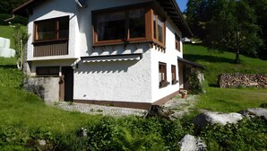 A two-story house with a balcony, a satellite dish, and a stone wall.