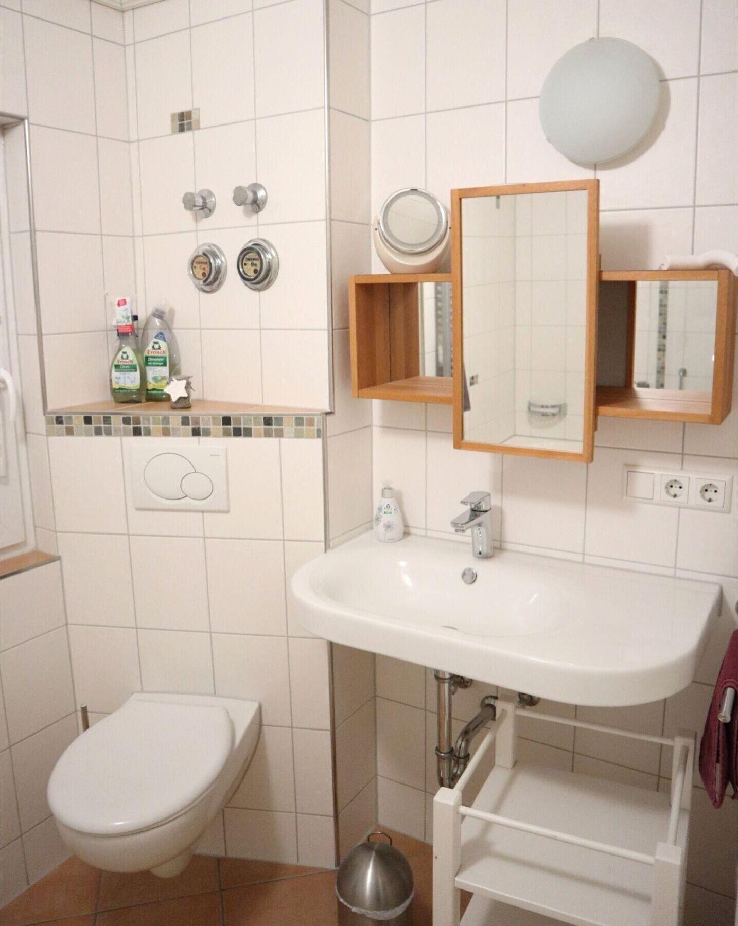 Ein Badezimmer mit Toilette, Waschbecken, Spiegel und Dusche.