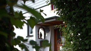 A stone pathway leading to a house with a porch, potted plants, and a window. - Apartment 'Am Brunnen' with Shared Terrace, Shared Garden and Wi-Fi (Titisee-Neustadt)